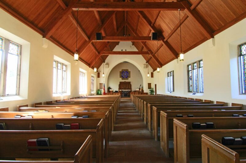 The empty interior of a traditional church sanctuary with wooden pews.